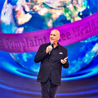 Will Bowen speaking in front of a Complaint Free World stage backdrop